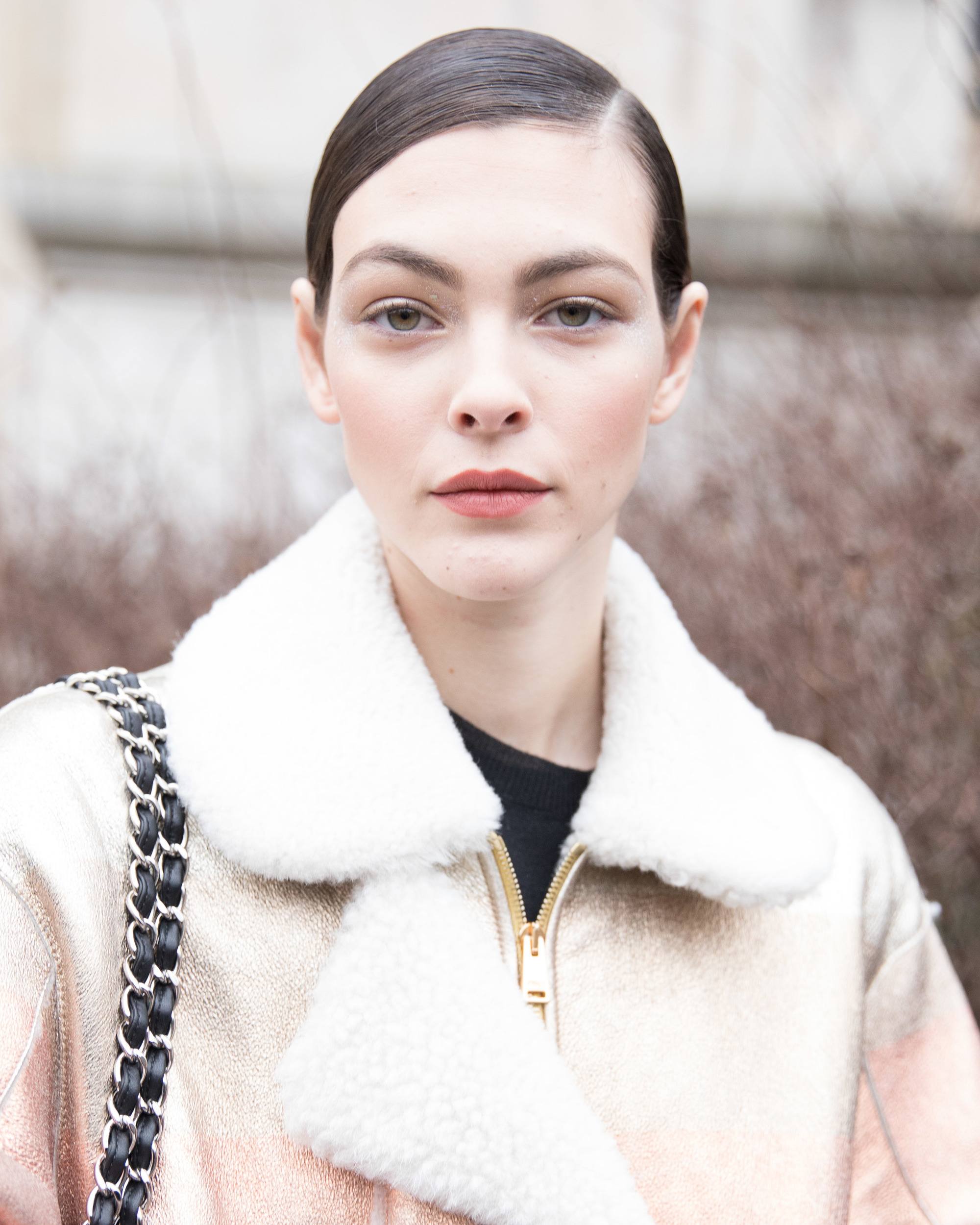 quick updos: close shot of woman with brown hair styled in side-parting smooth updo wearing a beige fluffy jacket