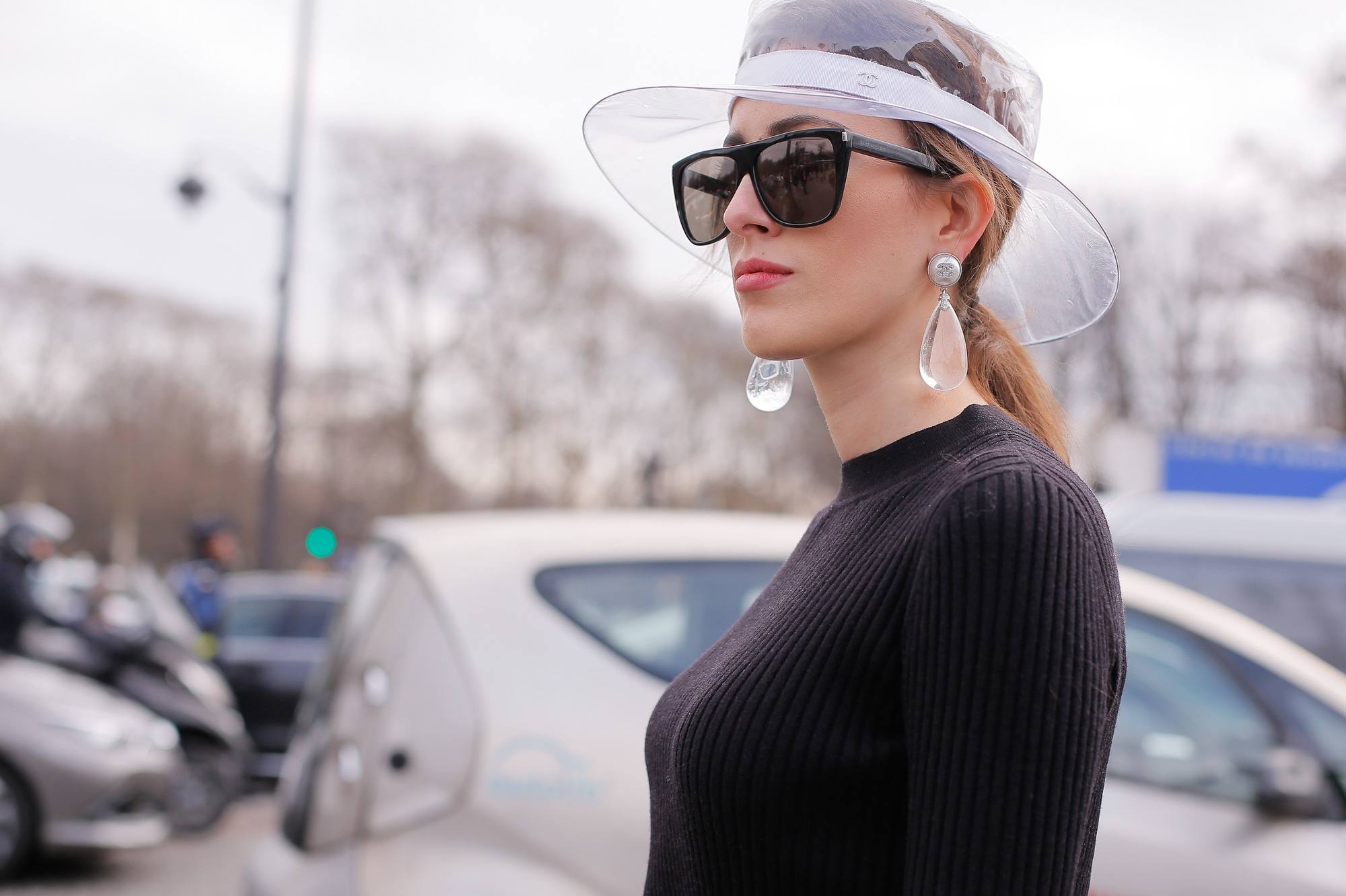 quick updos: street style image of woman with straight long blonde hair styled in a low ponytail worn with a clear plastic rim hat and dark sunglasses