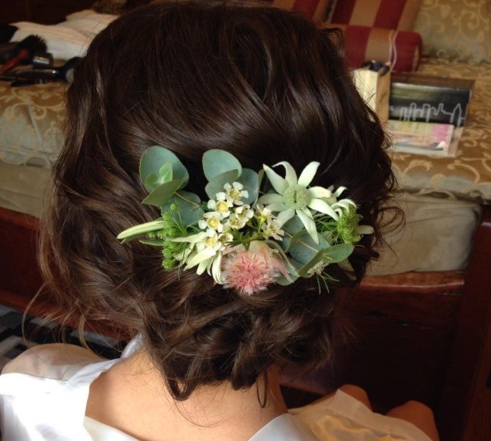 woman with dark brunette hair in a messy side bun