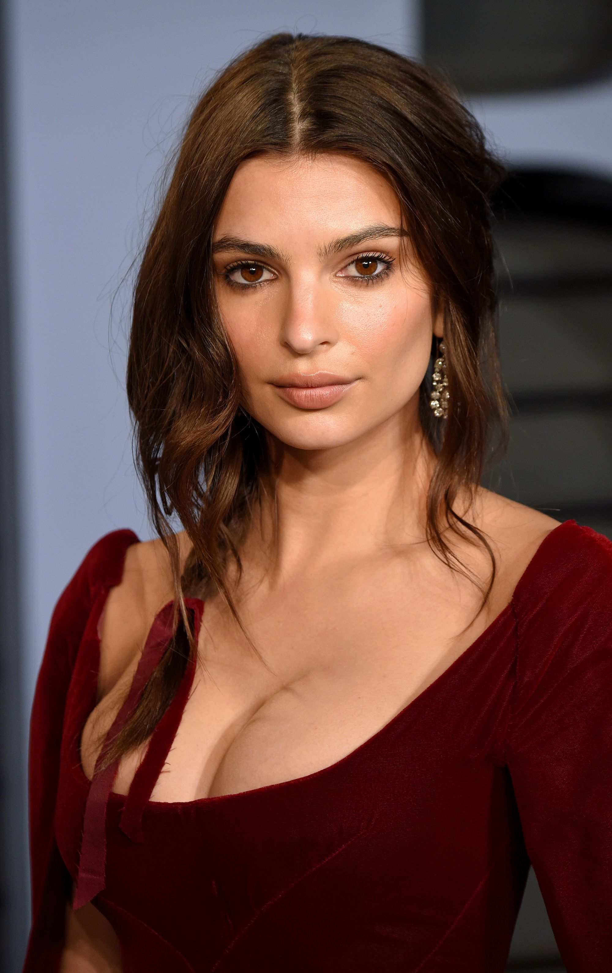 updos for medium hair: emily ratajkowski medium length brown hair styled in a wavy undone side braid with black ribbon at the end of the braid at red carpet event