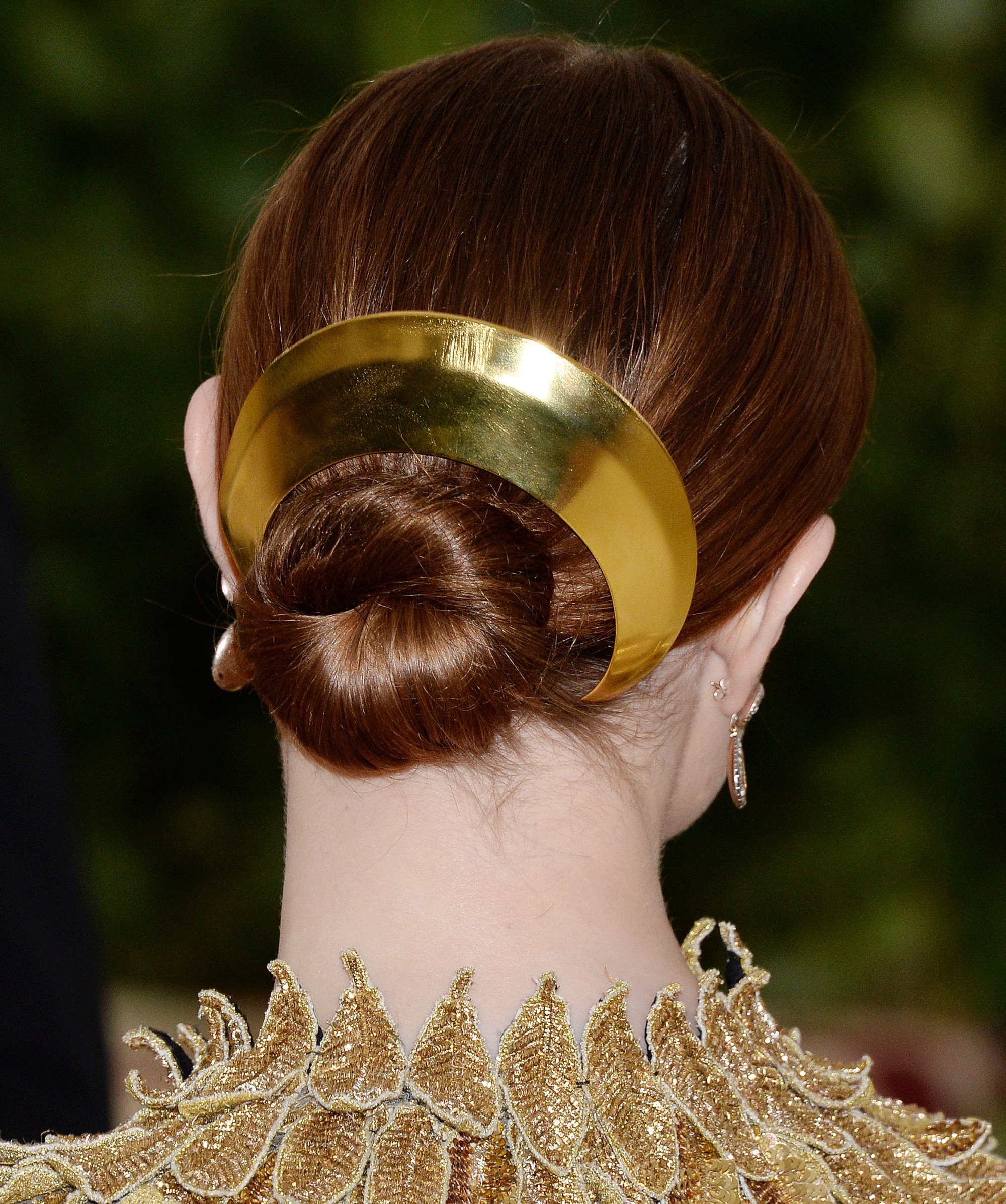 updos for medium hair: back view of evan rachel wood with auburn hair styled in a low smooth and sleek low bun updo with large gold hair accessory