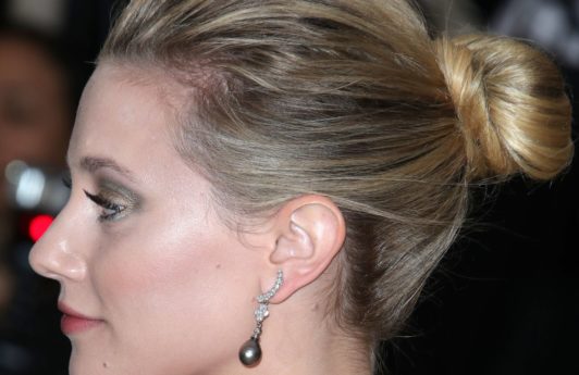 updos for medium hair: side view of lili reinharts blonde hair styled in a medium high bun hairstyle at red carpet event