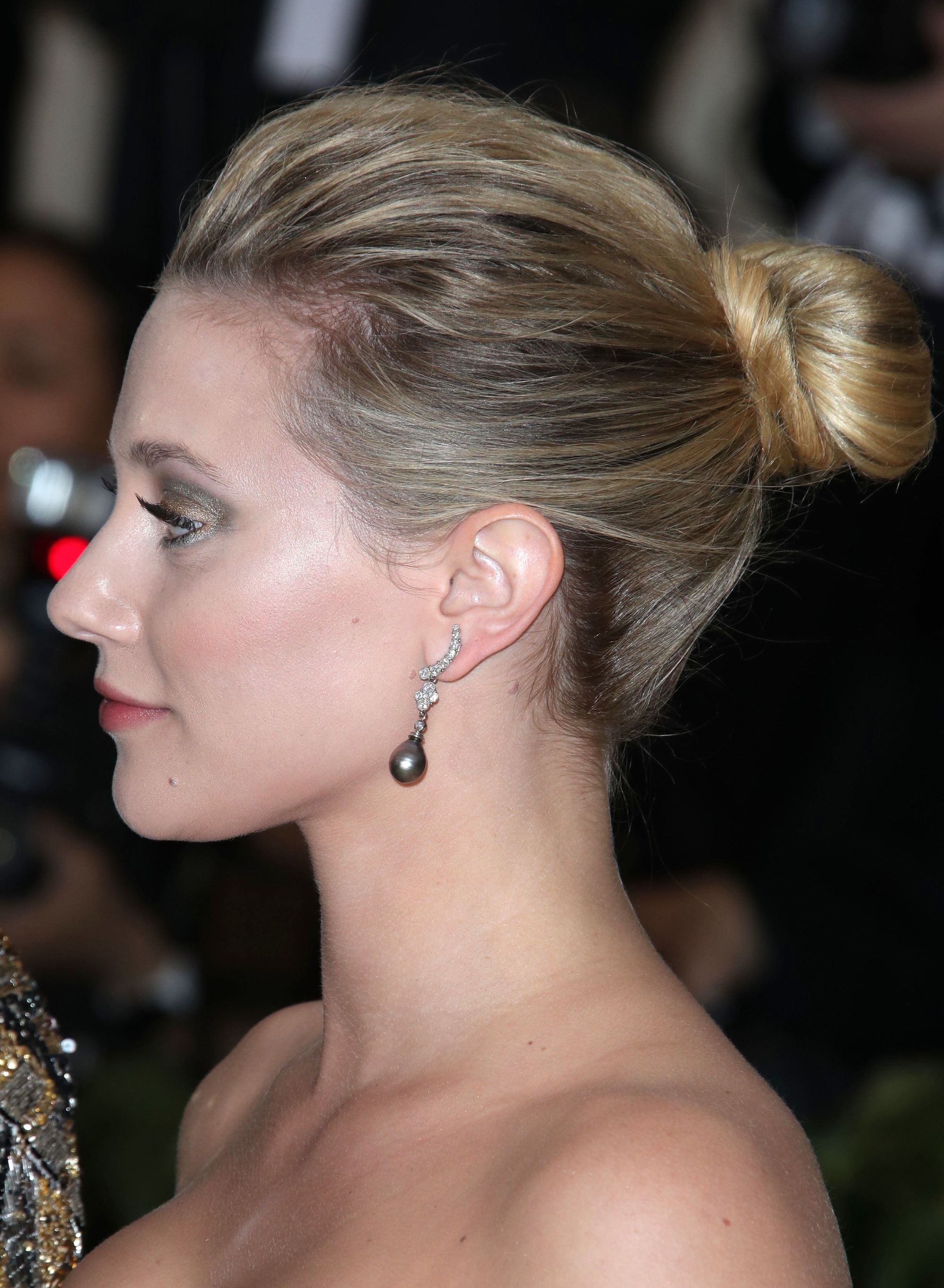 updos for medium hair: side view of lili reinharts blonde hair styled in a medium high bun hairstyle at red carpet event