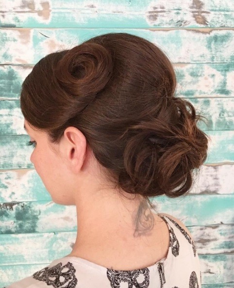 Bridal updos for long hair: Close up shot of a woman with long medium brown hair styled into vintage-inspired curled updo hairstyle.
