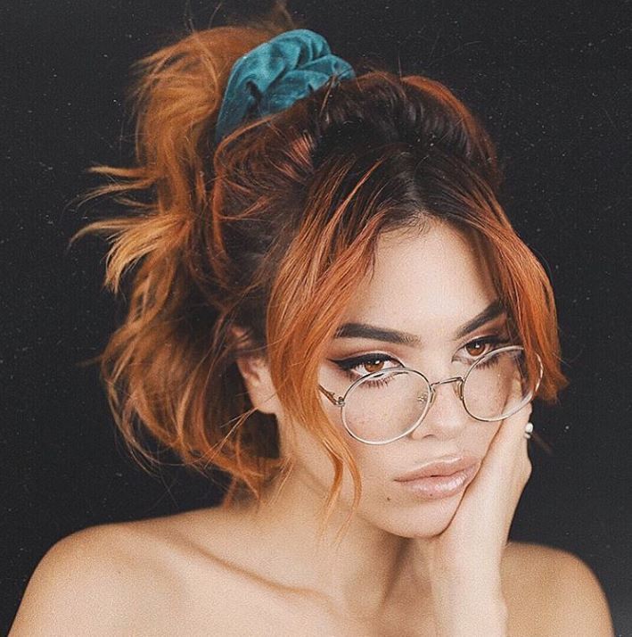 Short ombre hair: Woman with oarange ombre hair in half-up, halfd-won ponytail with a fringe wearing glasses.