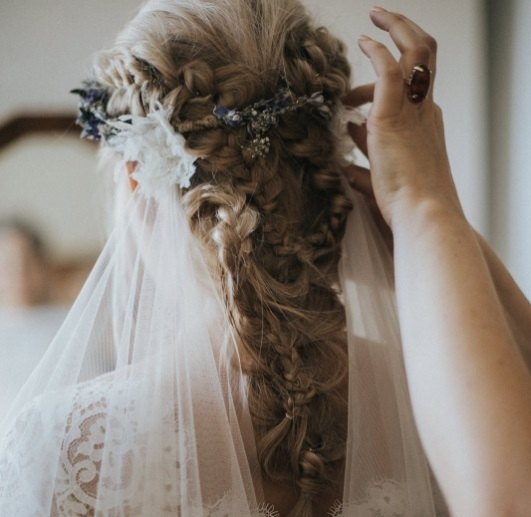 back view of a brunette bride with her hair in an intricate boho braid with a veil