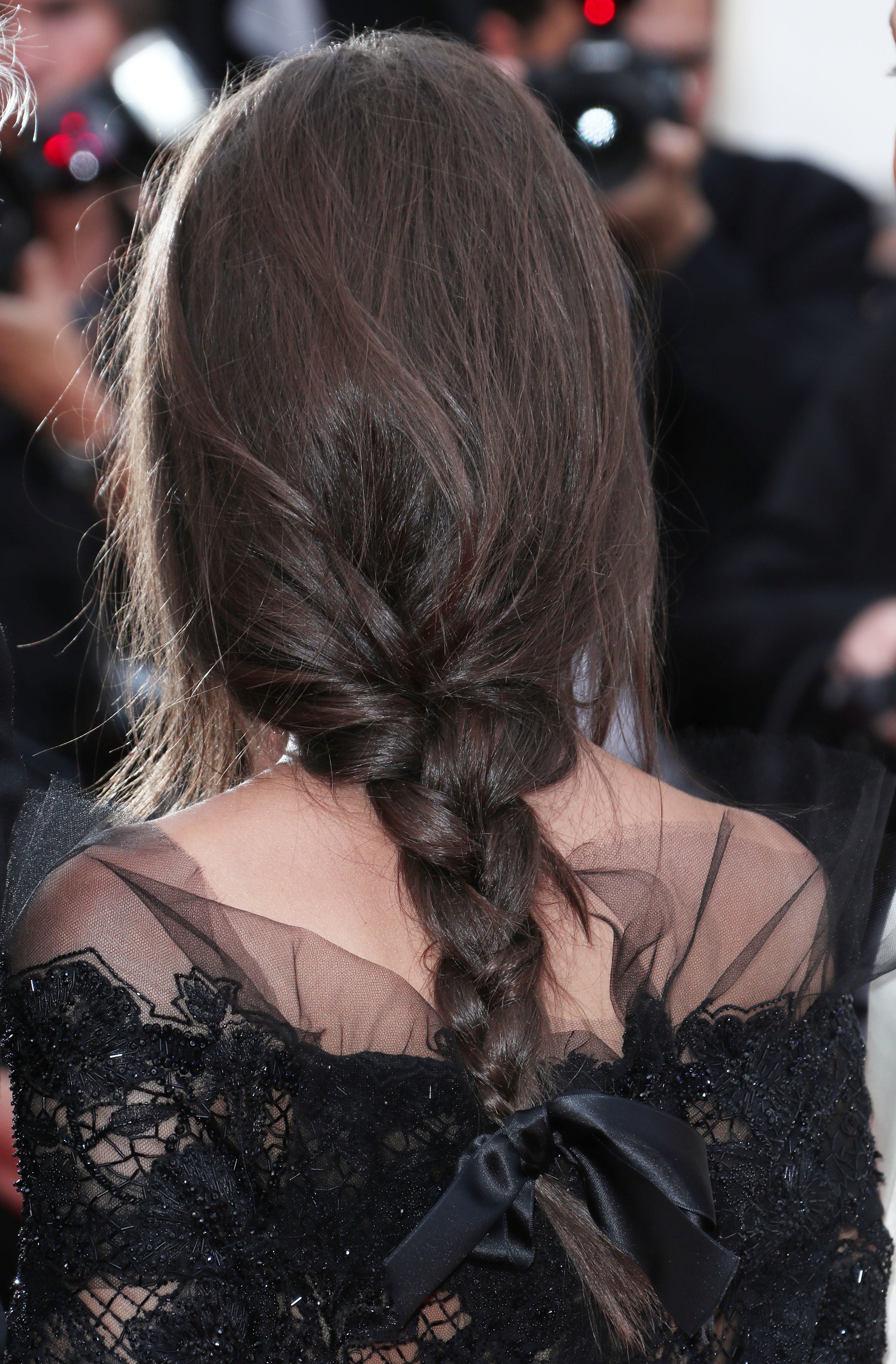 brunette with her hair in a braid with a black ribbon hair tie