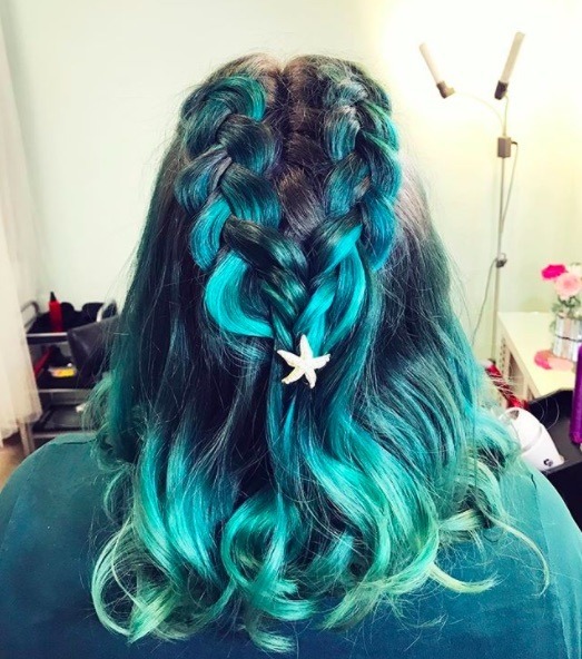 back view of a woman with blue and green hair and double dutch braid style