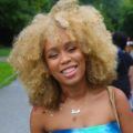 woman in park with buttermilk blonde afro hair colour smiling at curlfest