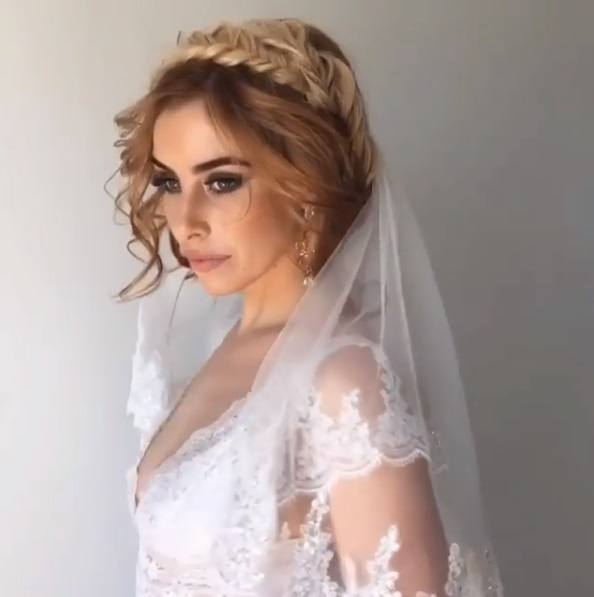 bride with caramel blonde and brown hair in a fishtail crown braid with a veil wearing a lace wedding dress