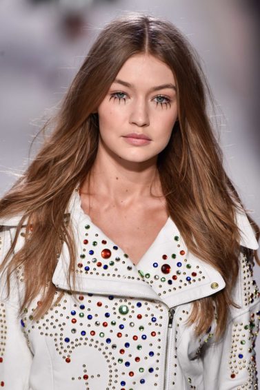 model gigi hadid on the runway with her signature long wavy hair