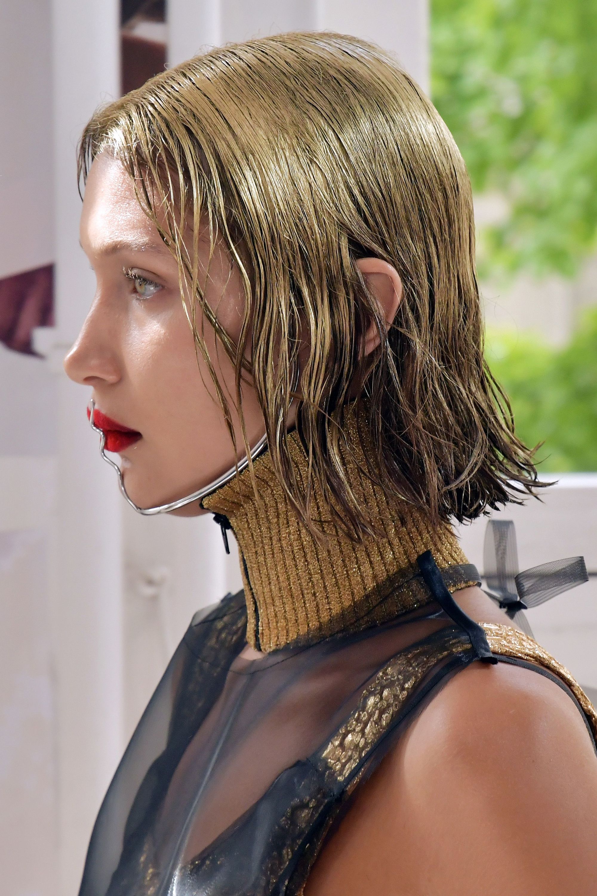 Bella hadid on the Maison Margiela runway with spray painted golden hair with red lips and black outfit