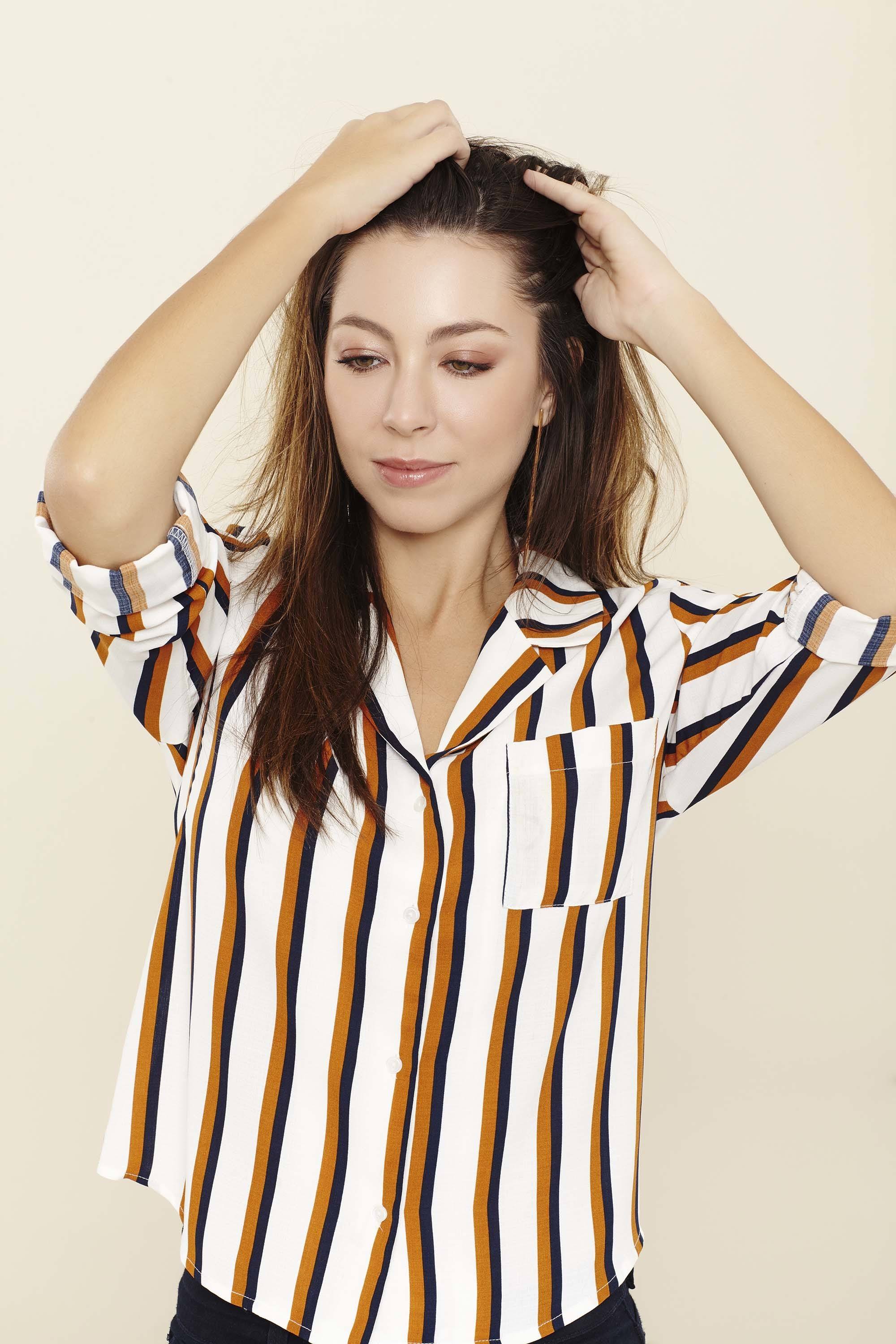 Shampoo full guide: Woman touching her long brown straight hair wearing a brown and white striped shirt.