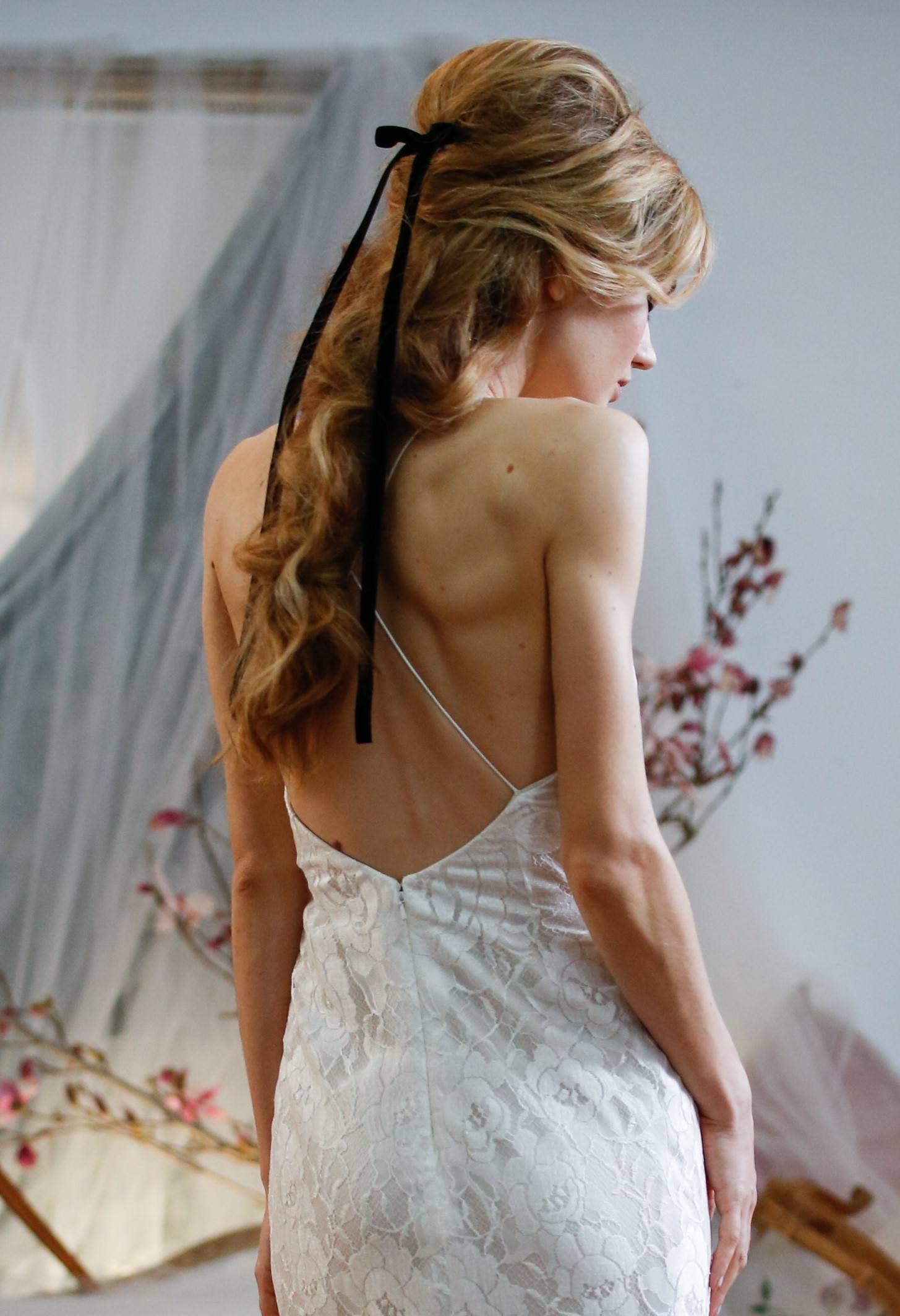 bridal model with her blonde hair in a half up half down hairstyle with a black ribbon accessory