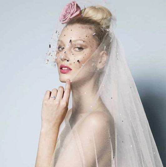 blonde bride with her hair in a high bun with a veil and pink flower hair accessory