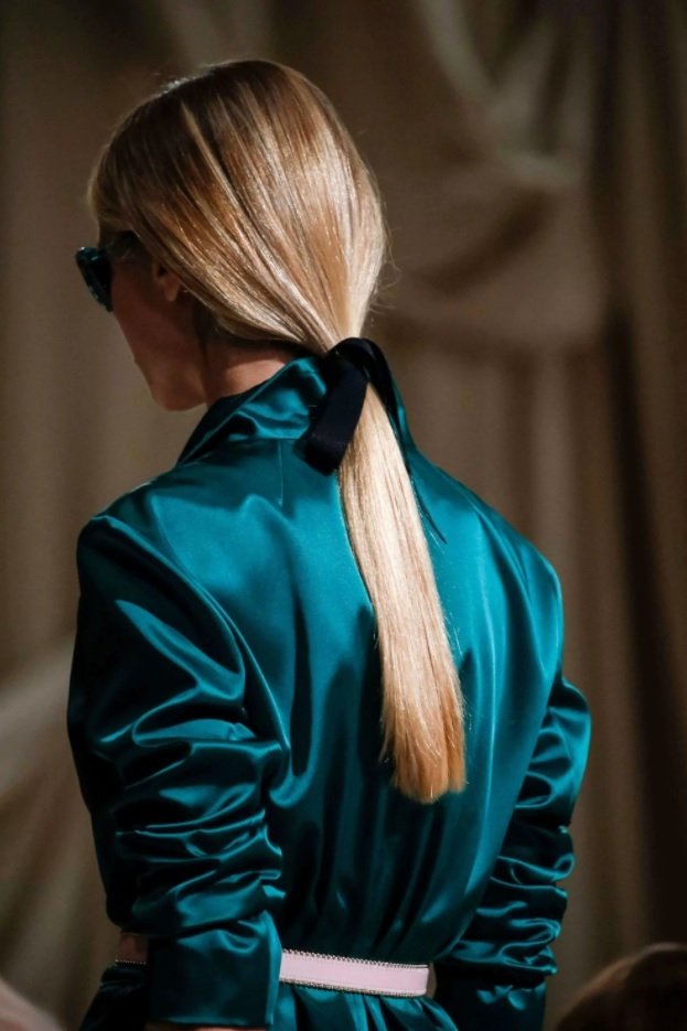 blonde model on the runway with her hair in a low ponytail with a black ribbon hair accessory