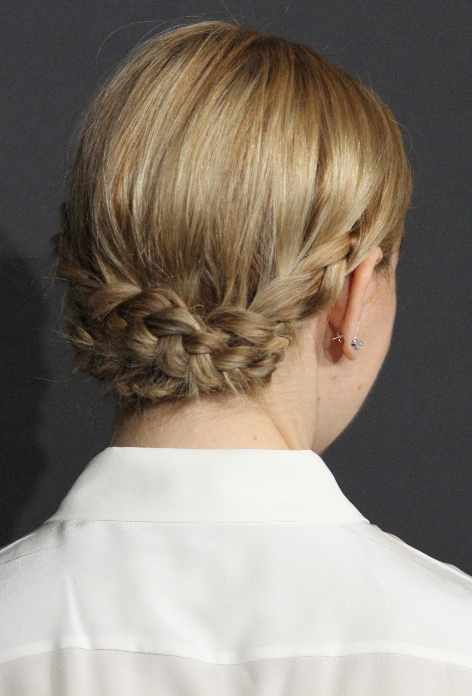 back view of zosia mamet with blonde hair styles in a low braided updo wearing a white short