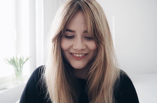 blonde woman with medium length hair and bardot bangs