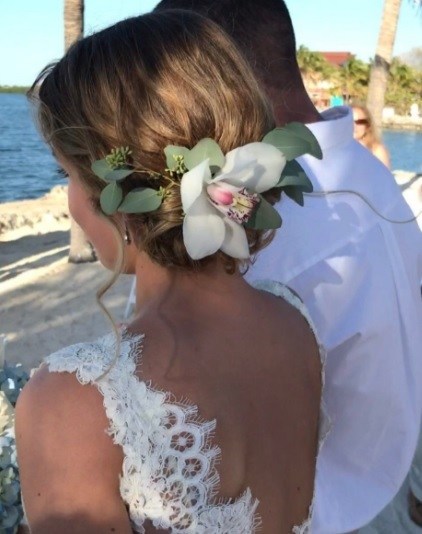 brunette woman on the beach in a wedding dress with her hair in a floral updo