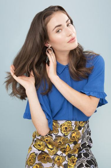 model touching hair wavy hair wearing blue and floral print trousers