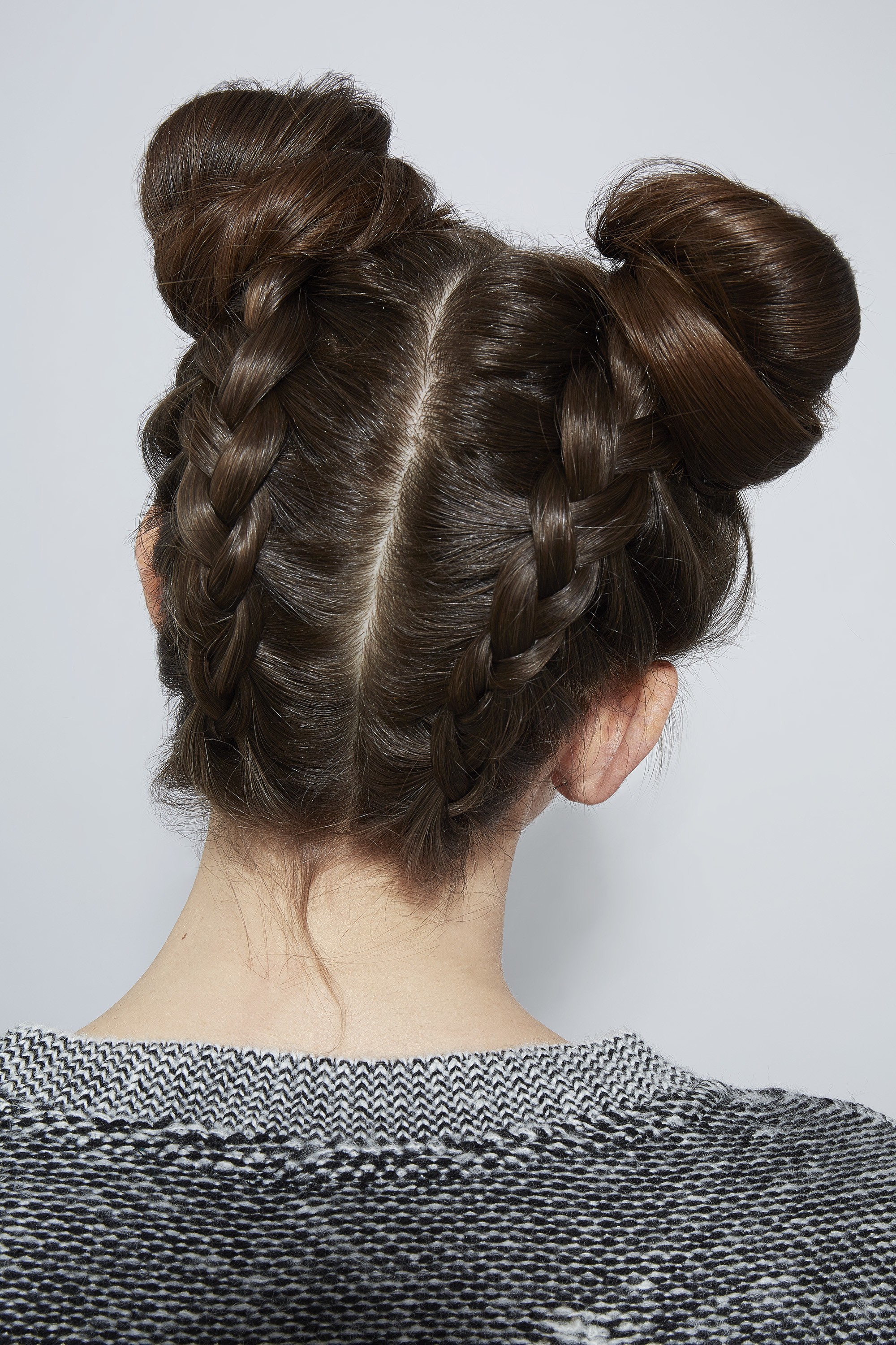 Braids for long hair: Woman with dark brown hair in dutch braids space buns.