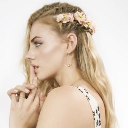 Braids for long hair: Woman with long blonde wavy hair with side floral braid wearing summer dress top.