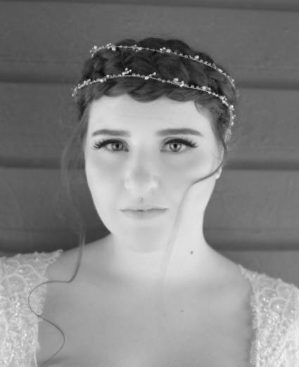 black and white face on photo of a bride with her dark hair in a crown braid updo with a crystal headpiece