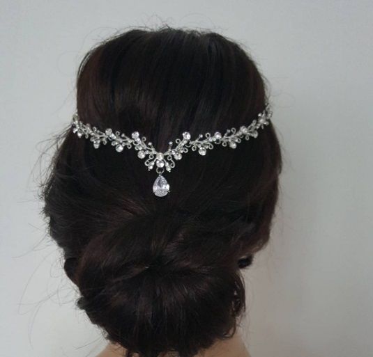 woman with dark brunette hair in an updo style with a crystal headpiece