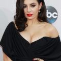 Charlie XCX wears her black hair in side parting with glamorous waves and black off the shoulder dress at American Music Awards 2014