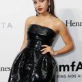 Charli XCX wears her black hair in high bouffant ponytail with front section smoothed back the look is finished with a black strapless dress