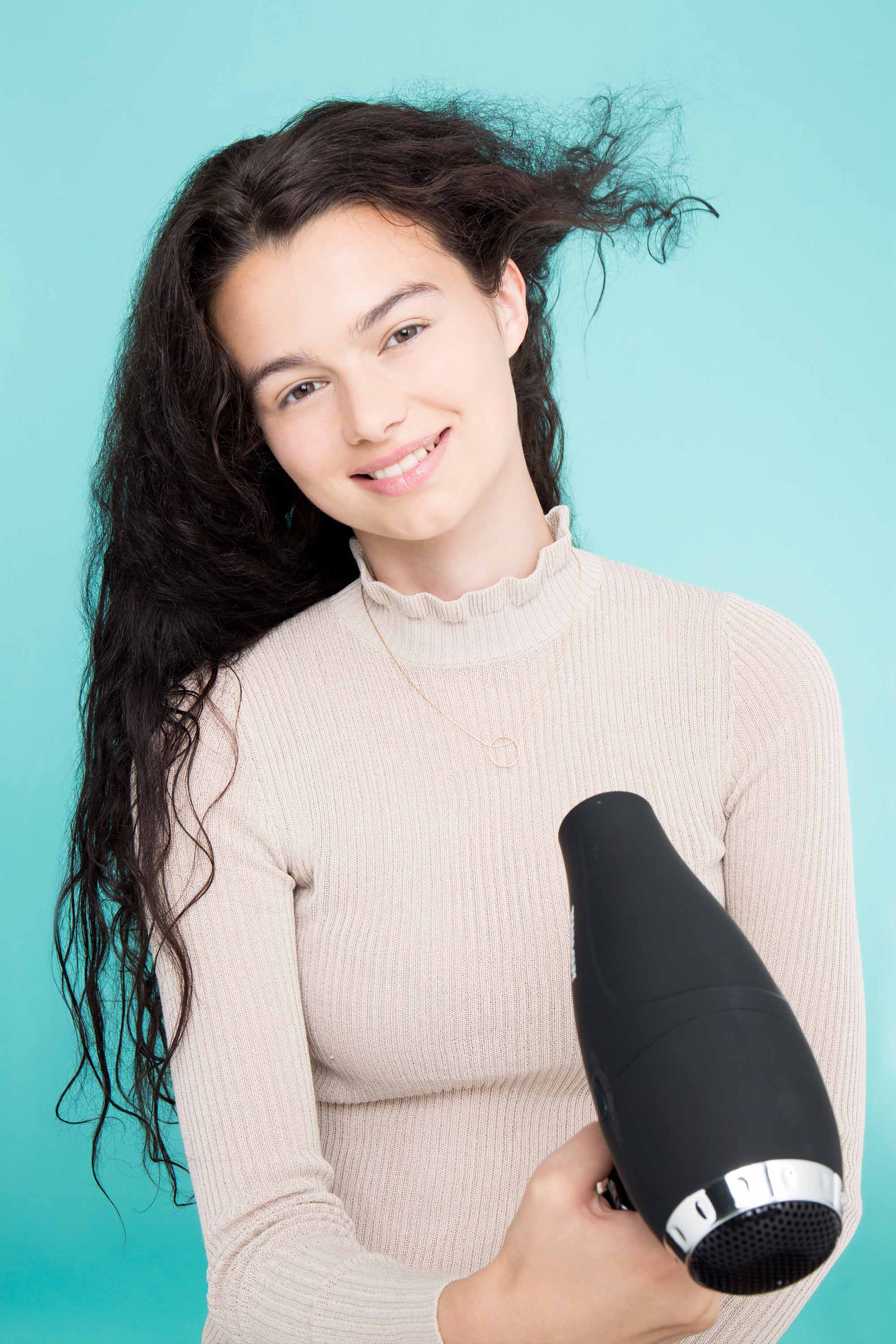 woman with long frizzy dark hair drying her hair