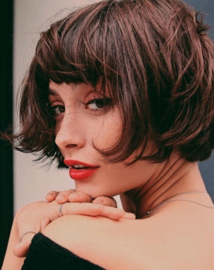 brunette woman with a french bob haircut looking over her shoulder