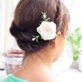 back view of a woman with brunette hair in a milkmaid twist hairstyle with a pink flower hair accessory