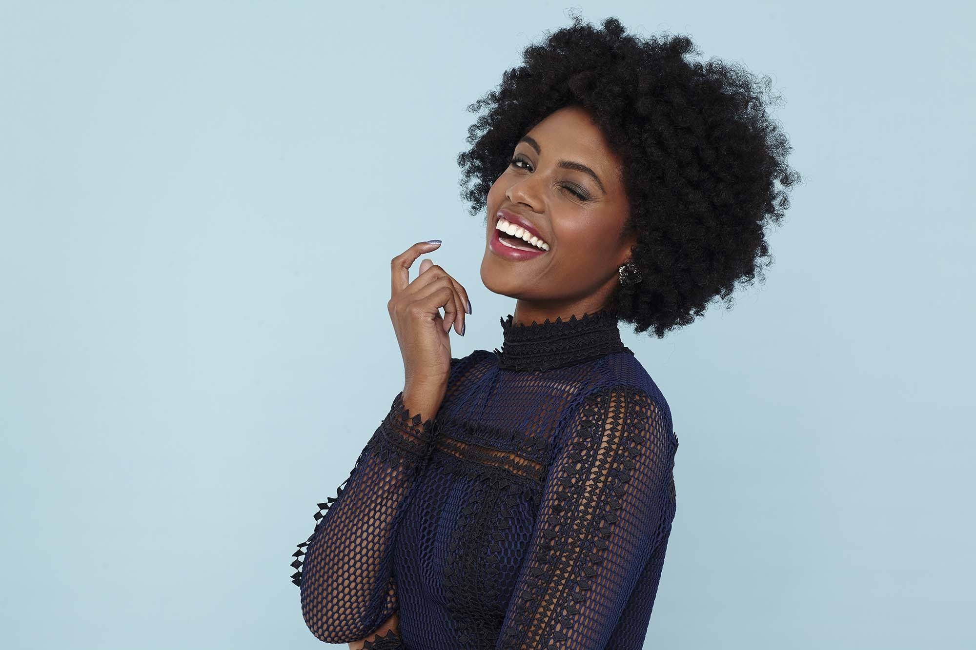 Best hair serum for dry hair: Model with short naturally curly hair wearing a lace blouse top.