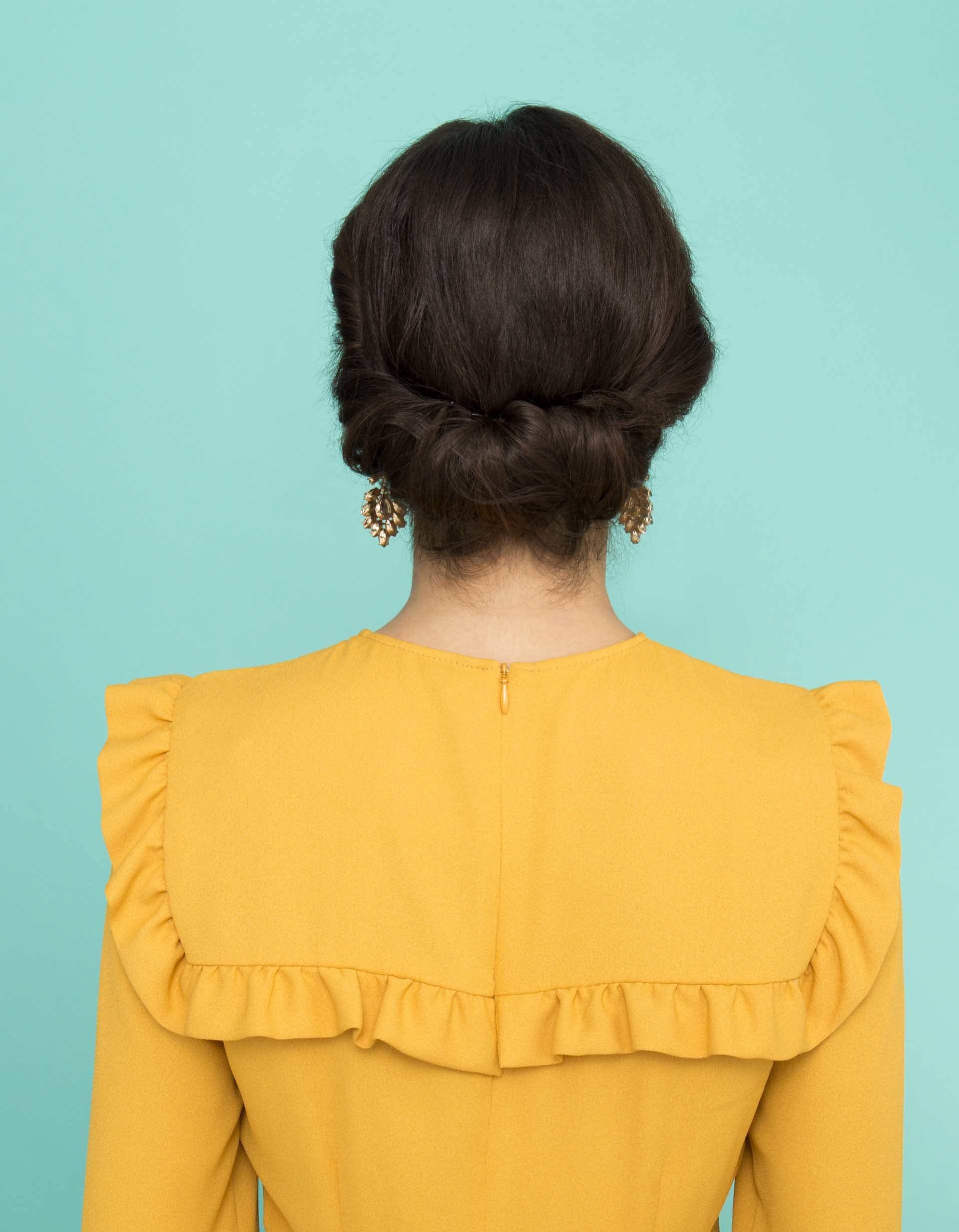 prom hairstyles for medium hair: dark brown haired model showing off gibson tuck hairstyle from behind while wearing bright yellow dress