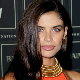 sarah sampaio on the balmain red carpet with dark brown hair styled to the side wearing red