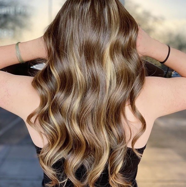 Balayage long hair: Back view of a woman with long wavy honey brown balayage hair