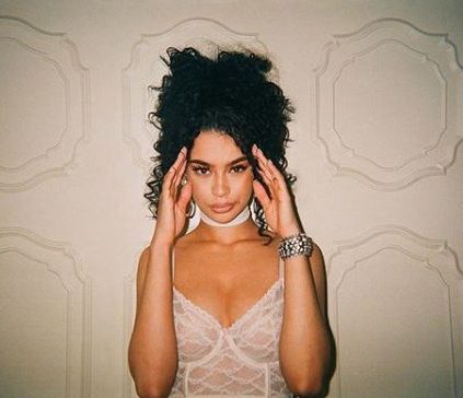 Rainy Milo with curly black hair in high ponytail against cream backdrop