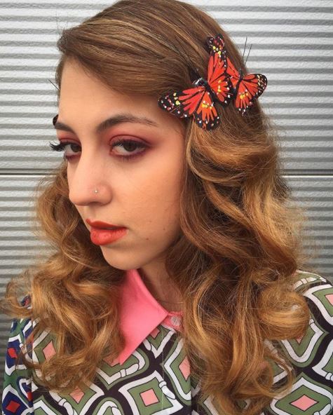 girl with golden brown hair with vontage waves and red butterfly clips