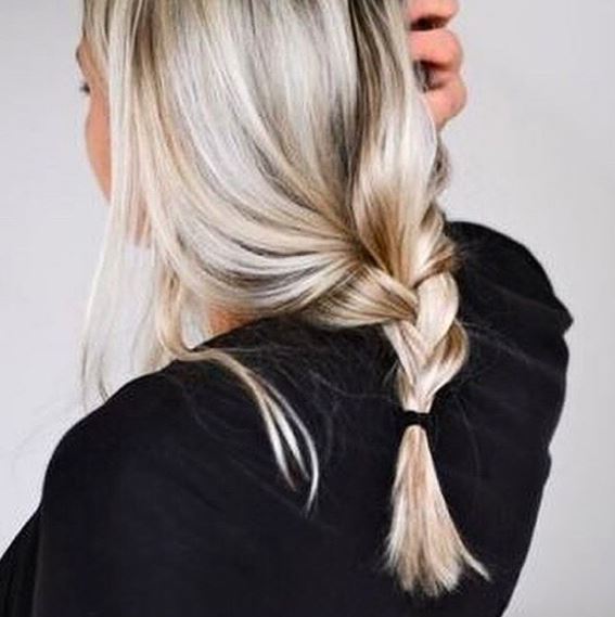 back shot of a woman with icy blonde hair and highlights in a loose plait