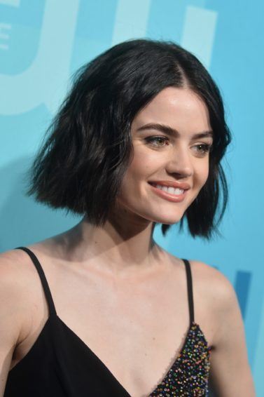 lucy hale with with wavy black hair on the red carpet smiling