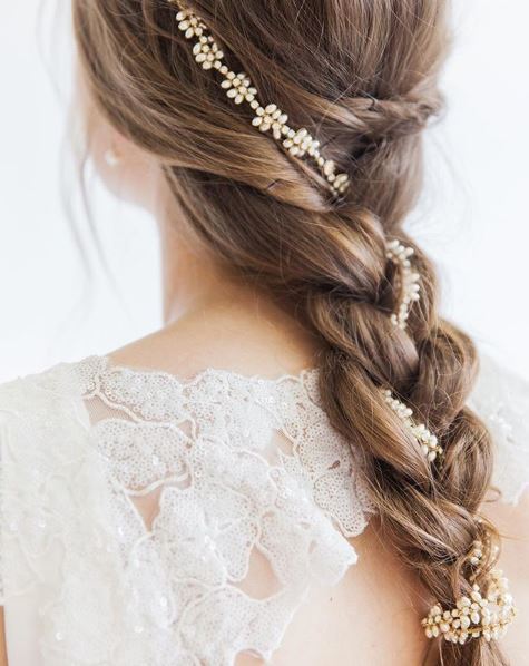 The back view of a bride with a loose braid and a chain flower accessory