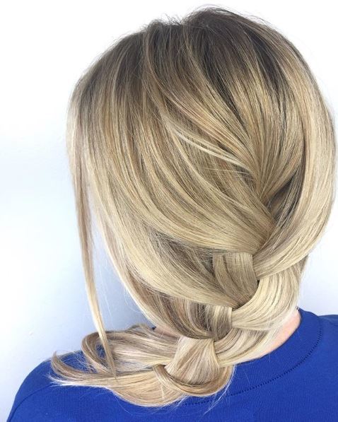 The back view of a blonde woman with a loose braid over her shoulder