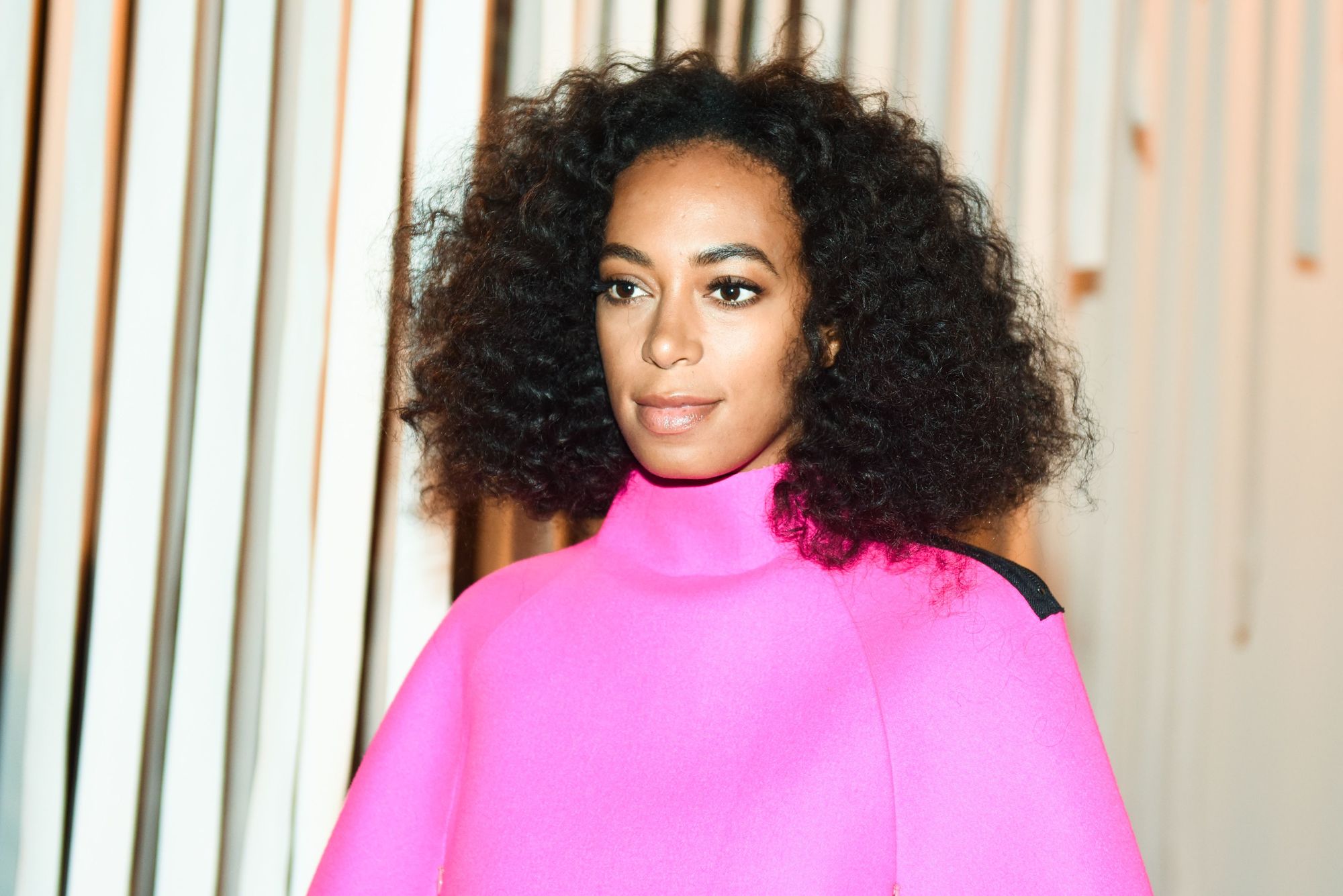 picture of solange knowles with curly medium bob style, wearing pink jumper at a backstage show