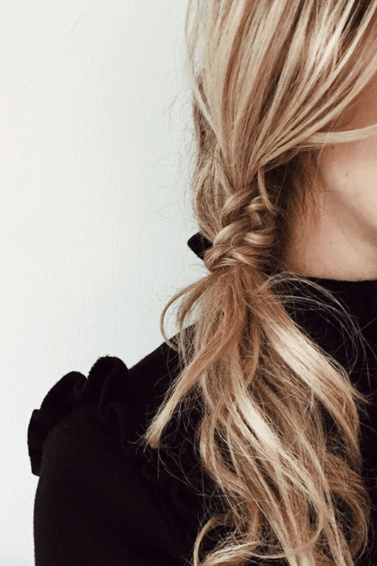 woman with messy staircase side braided ponytail hairstyle