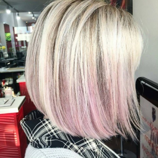 side shot of a woman with a blonde bob haircut with pink balayage