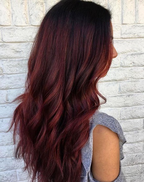 Balayage long hair: Side view of a woman with cherry red balayage curly hair
