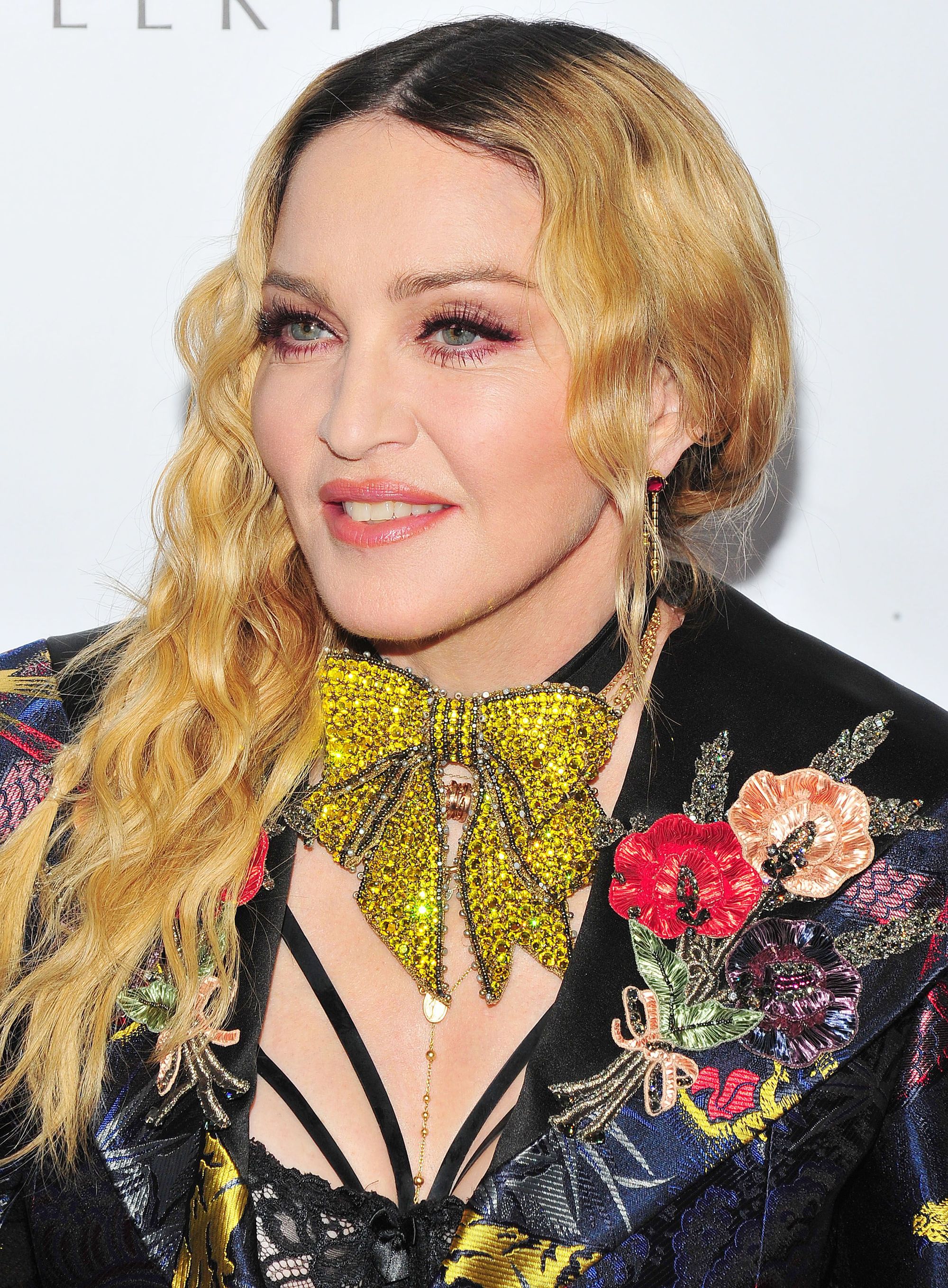 Madonna on the red carpet in 2016 with long blonde wavy hair swept over one shoulder.