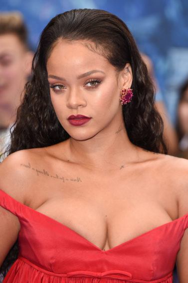 Rihanna with slicked back strands wearing red on the Valerian red carpet