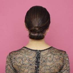 prom hairstyles for medium hair: brown hair model showing of low sleek wrapped tuck bun hairstyle from back view